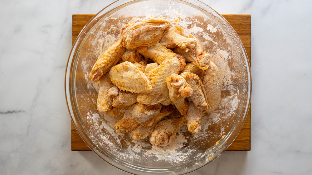 buffalo wings in glass bowl on wooden cutting board