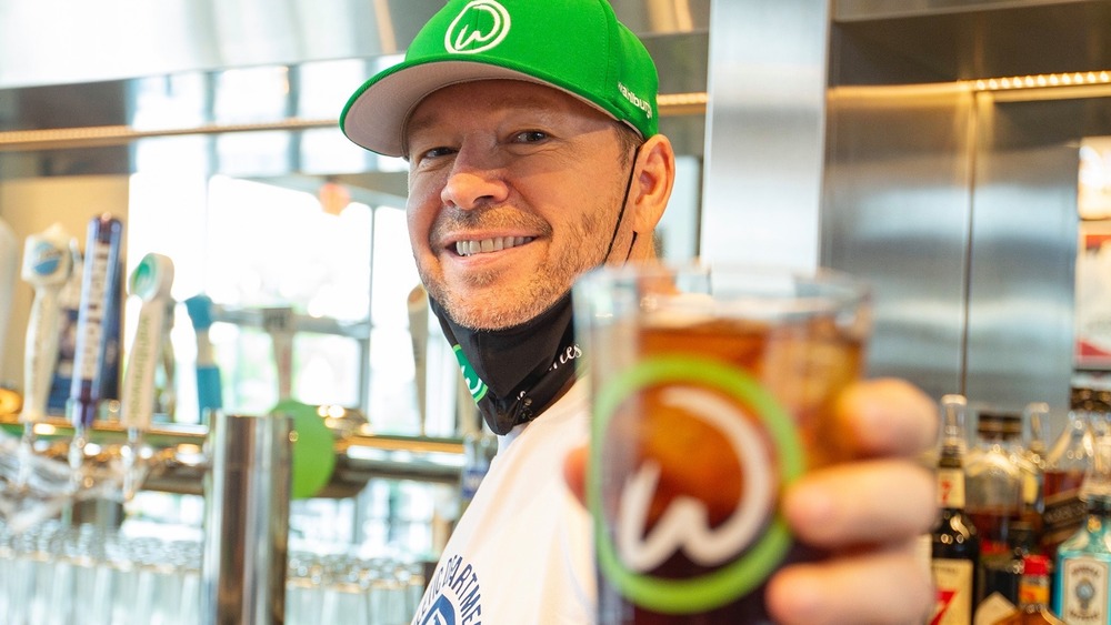 Wahlburgers Donnie Wahlberg holding drink glass towards camera