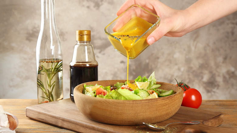 Hand pouring salad dressing