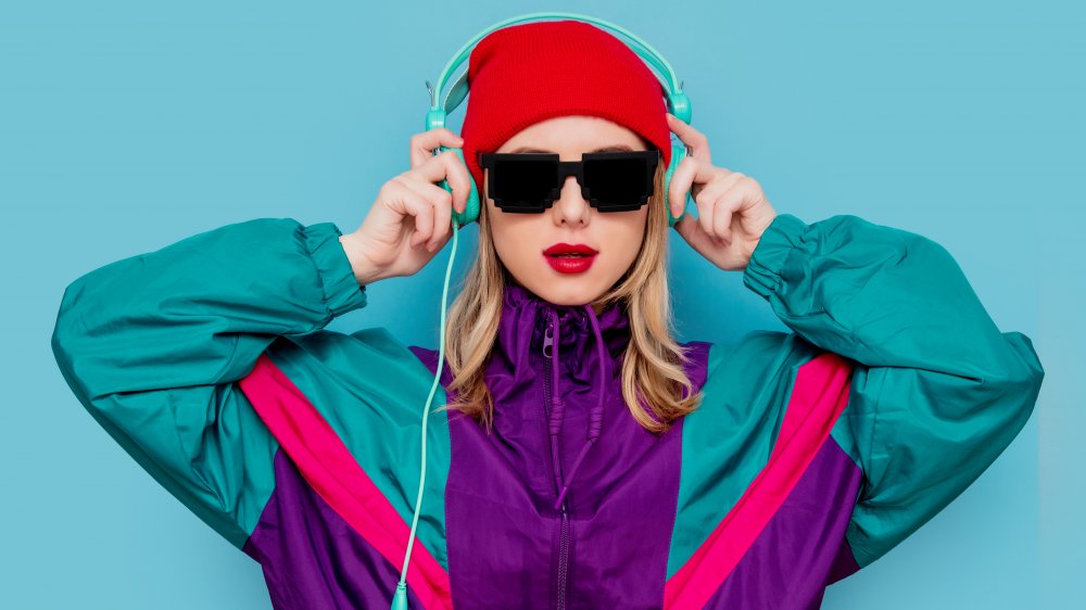 Young person wearing 90's gear, headphones, sunglasses