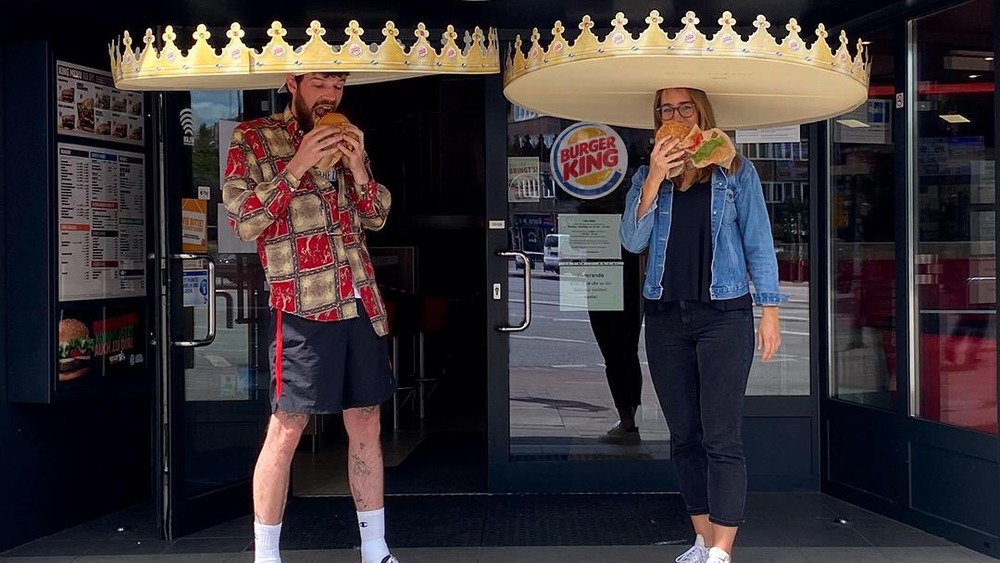 Man and woman eating Whoppers in six-foot paper BK Crowns