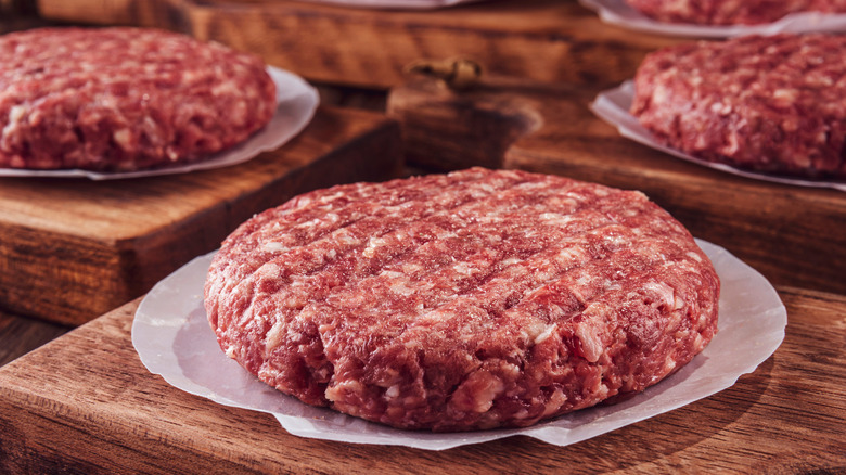 raw beef patties on wooden boards