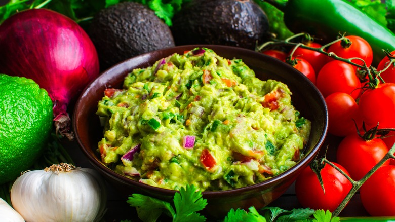 bowl of fresh guacamole surrounded by ingredients