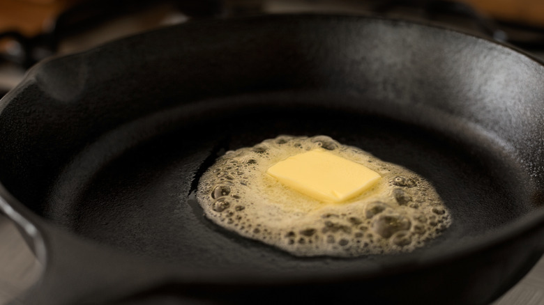 butter square melting in cast iron pan