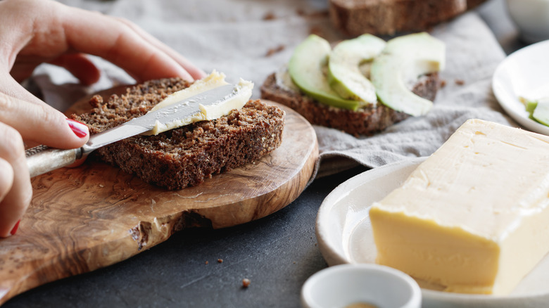 person buttering rye bread