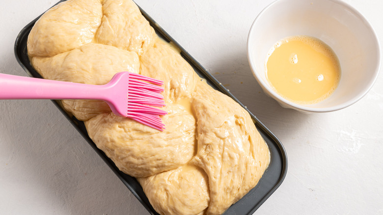 Brushing braided brioche dough with egg wash