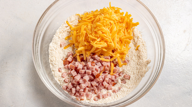 Bowl with flour, shredded cheddar cheese, and diced ham