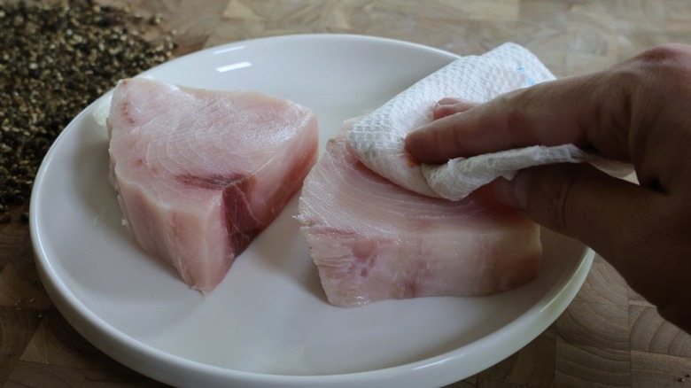 patting swordfish steaks with paper towel