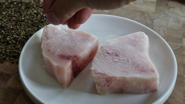 sprinkling salt over swordfish steaks