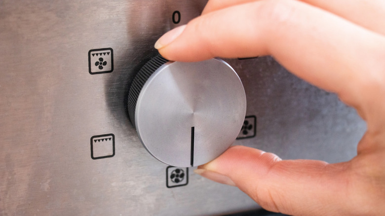 Hand turning dial on oven