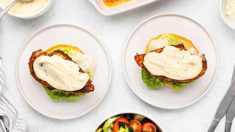 Two open Cajun chicken Alfredo sandwiches on plates