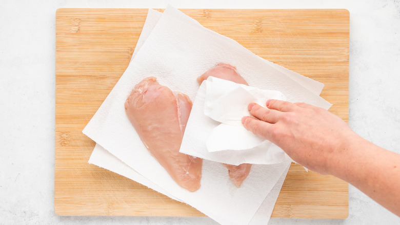 Patting chicken breasts dry with kitchen paper