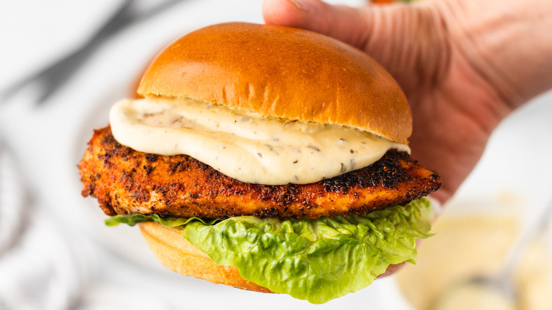 Hand holding Cajun chicken Alfredo sandwich