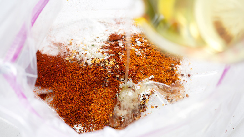 Adding oil to the bag of spices for Cajun firecracker crackers