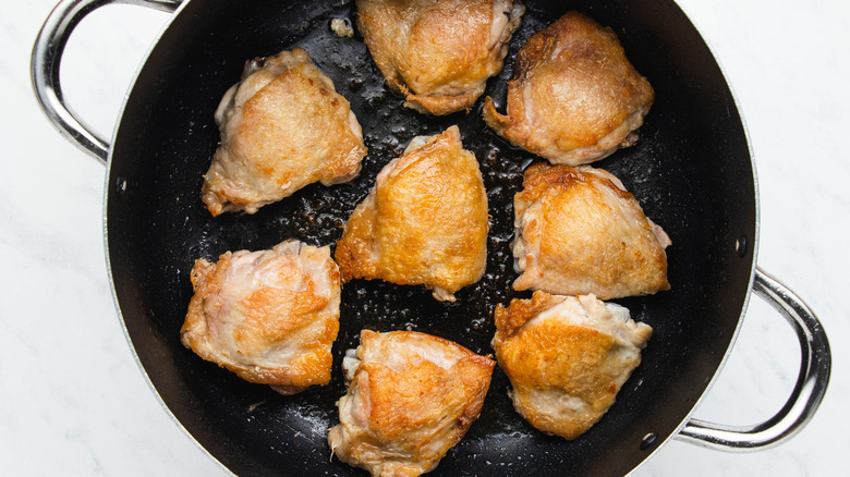 chicken thighs cooking in skillet