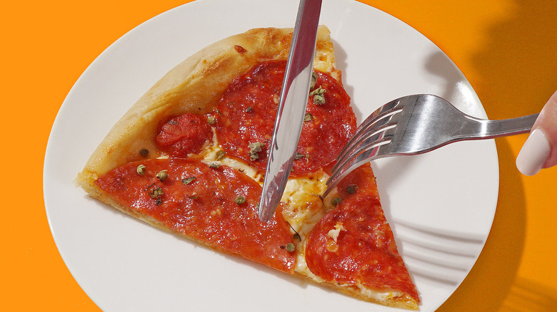 Person cutting pizza with knife