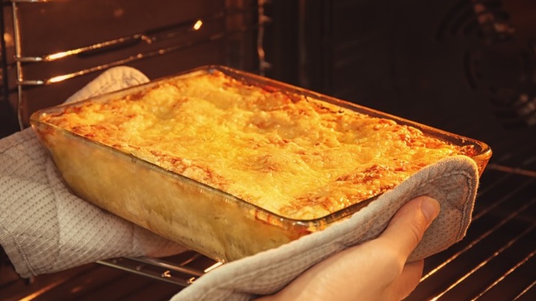 Hands placing casserole in the oven