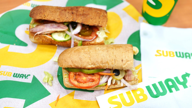 Two Subway sandwiches sitting on table 