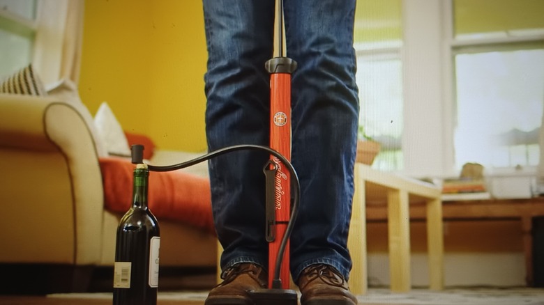 Man's feet near a bike pump and needle in wine bottle