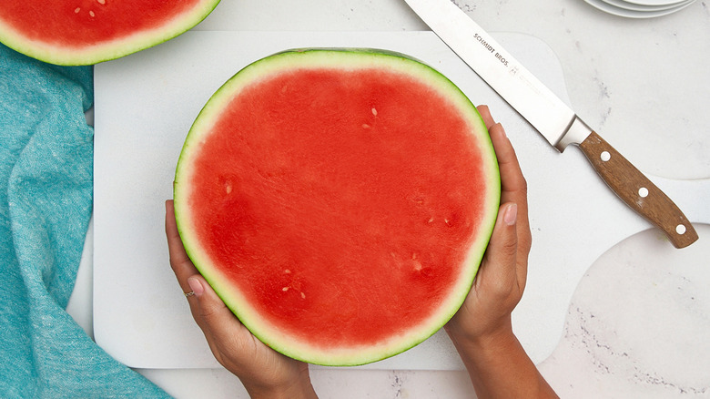 hands holding cut watermelon