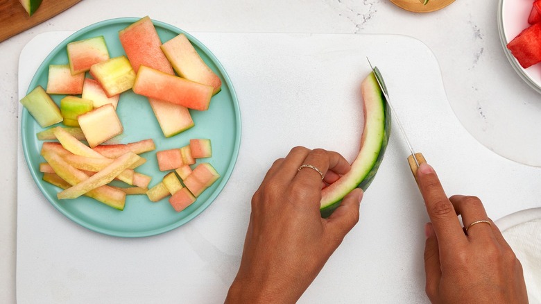 hands cutting watermelon rind