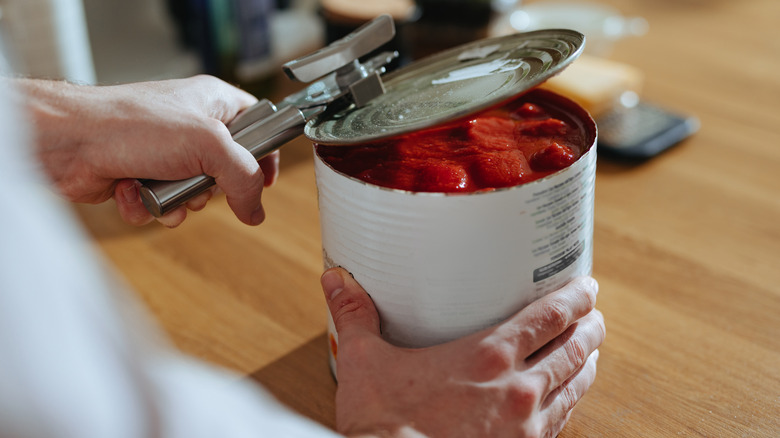 Person opening can of tomatoes