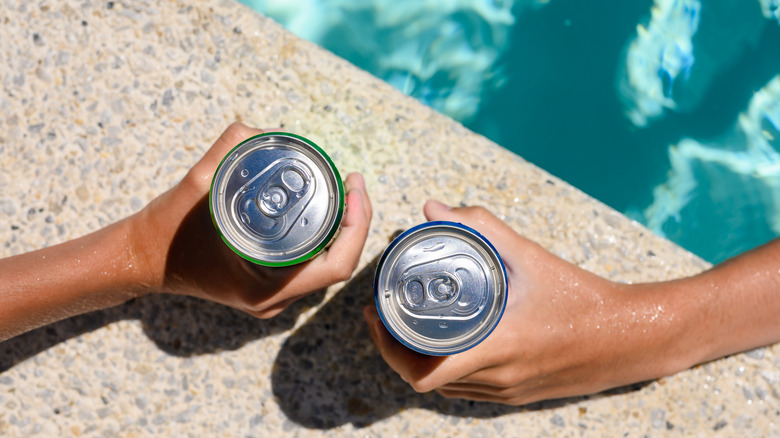 hands gripping canned beverages