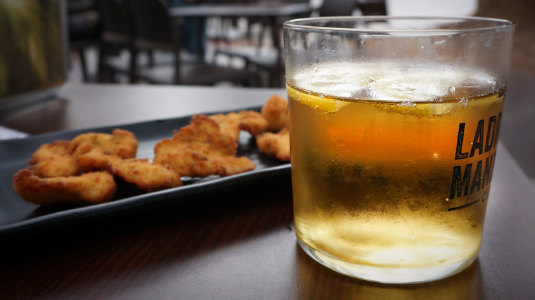 Cider in a glass with fried chicken on plate