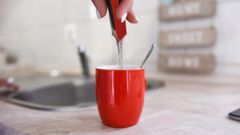 Pouring instant coffee into a mug