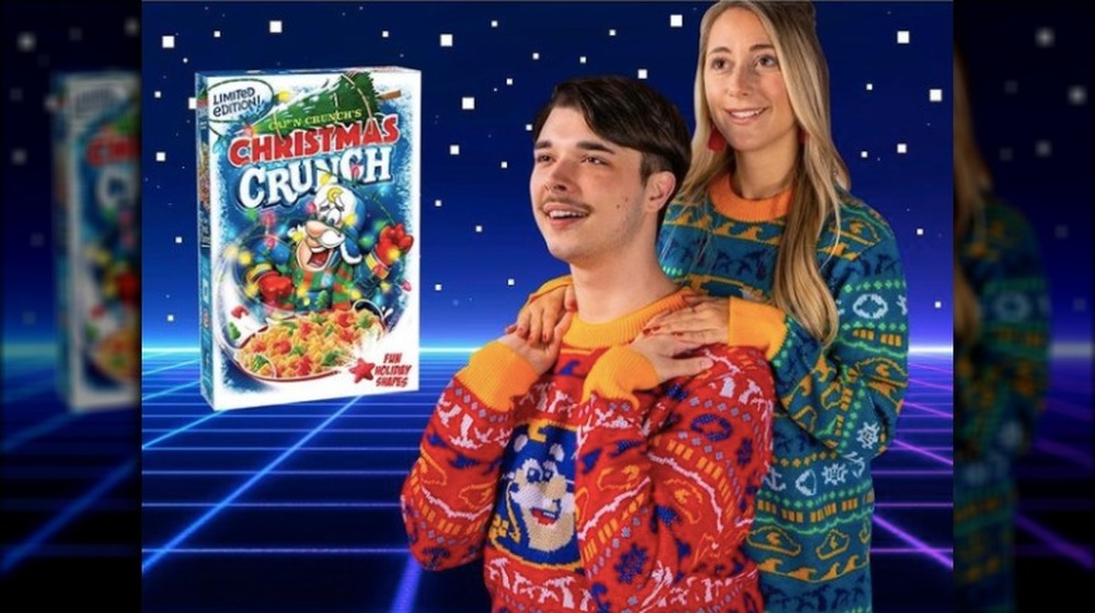 Two people wearing Cap'n Crunch Christmas sweaters