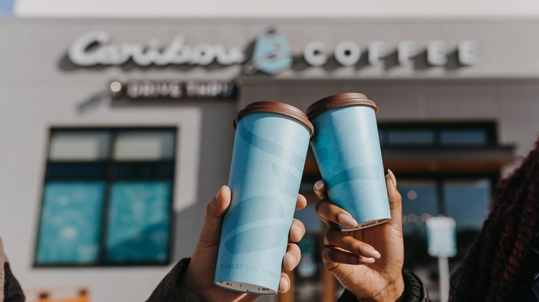 People holding coffee in front of Caribou Coffee