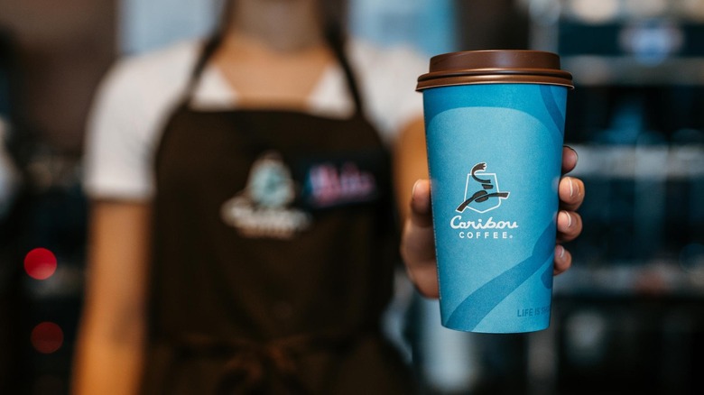 Employee holding Caribou Coffee cup