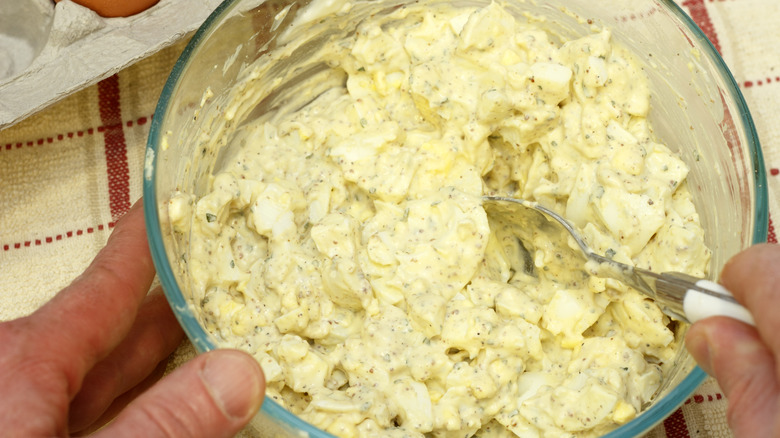 Person mixing egg salad in bowl