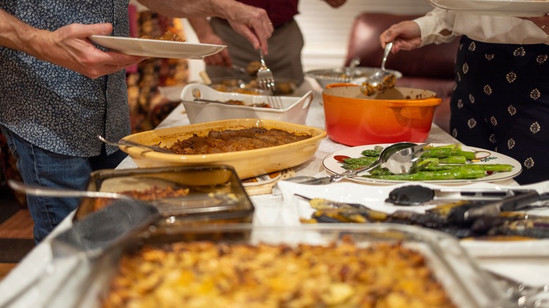 People serving themselves from casserole dishes 