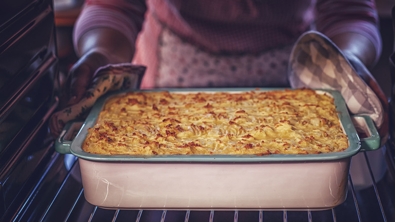Woman pulling casserole out of oven