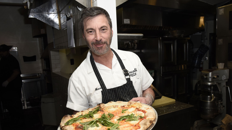 Mark Iacono holds pizza pie with fresh basil