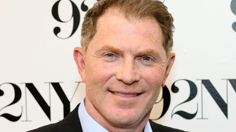 Bobby Flay smiling against 92NY background