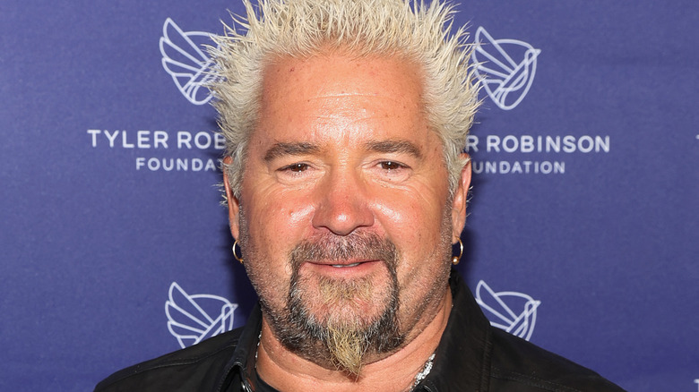 Guy Fieri poses against blue background