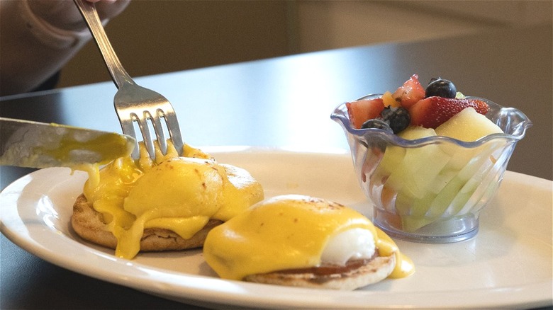 Person eating Eggs Benedict breakfast