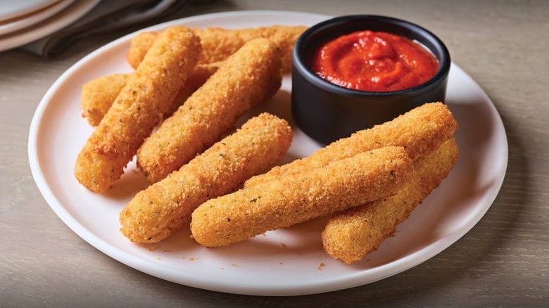 Mozzarella sticks on sauce on round plate