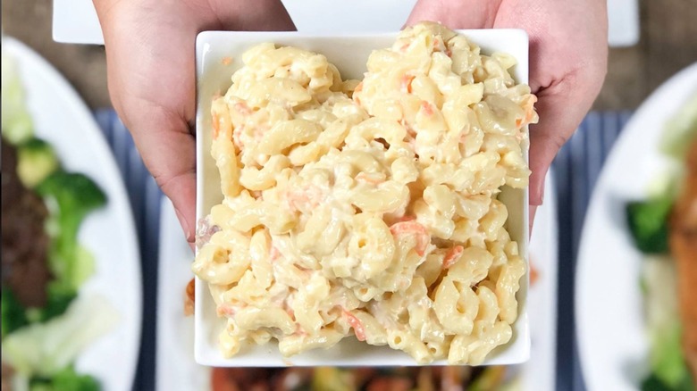 hands holding macaroni salad