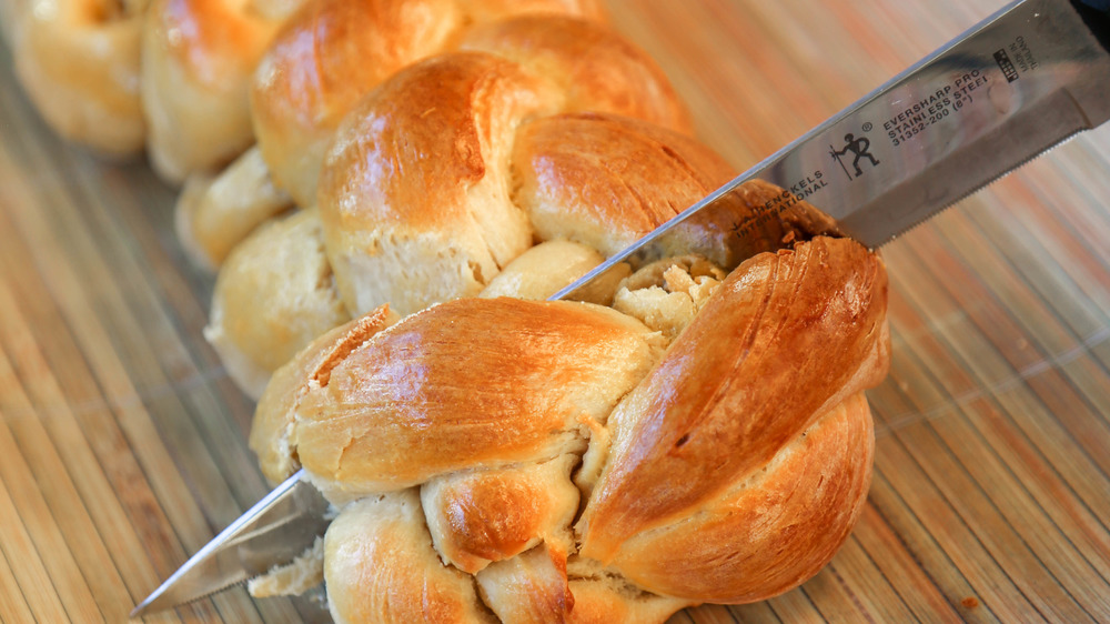 slicing into fresh challah bread 