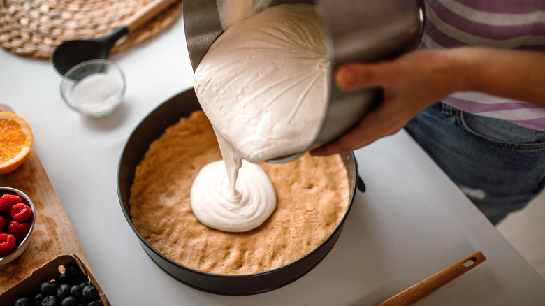 Pouring cheesecake over crust