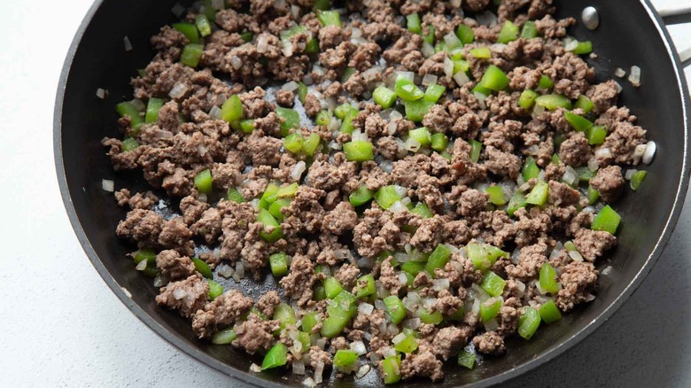 cooked beef, onions, and peppers in a skillet.