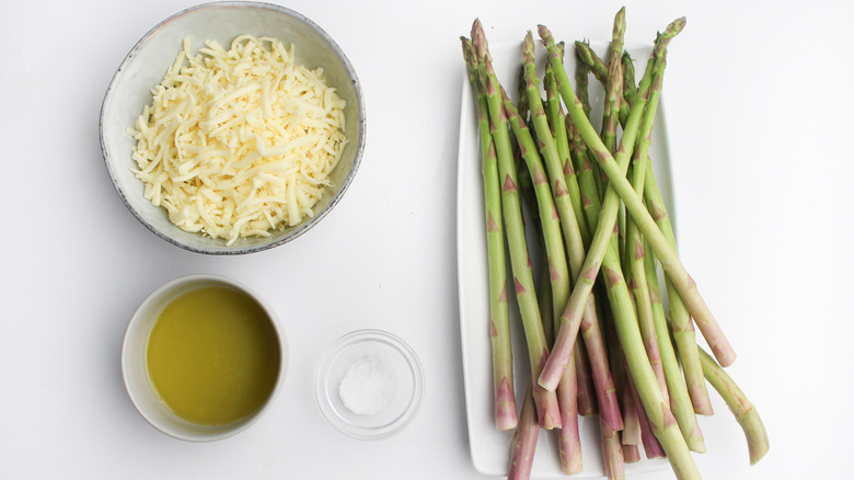 Dishes of cheese, oil, salt, and asparagus