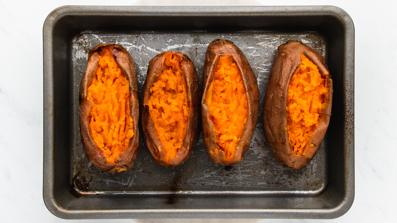 sweet potatoes sliced open in baking pan