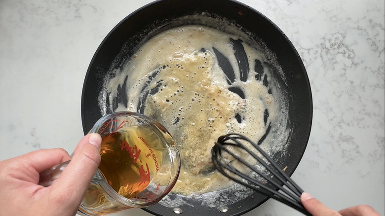 hand pouring liquid into pan