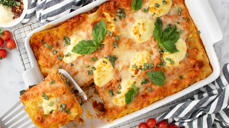 lasagna in a white pan surrounded by black-striped napkins