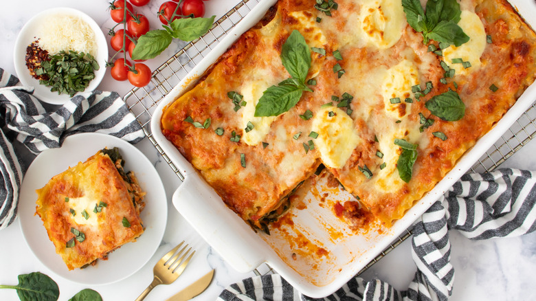 lasagna in a white pan surrounded by black-striped napkins