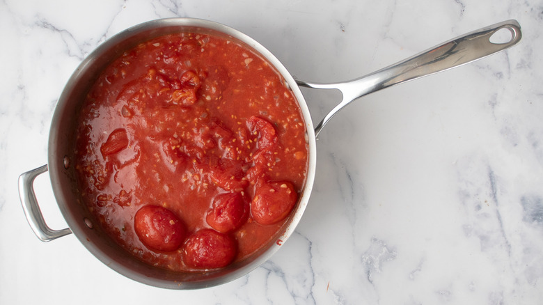 whole and crushed canned tomatoes in a frying pan